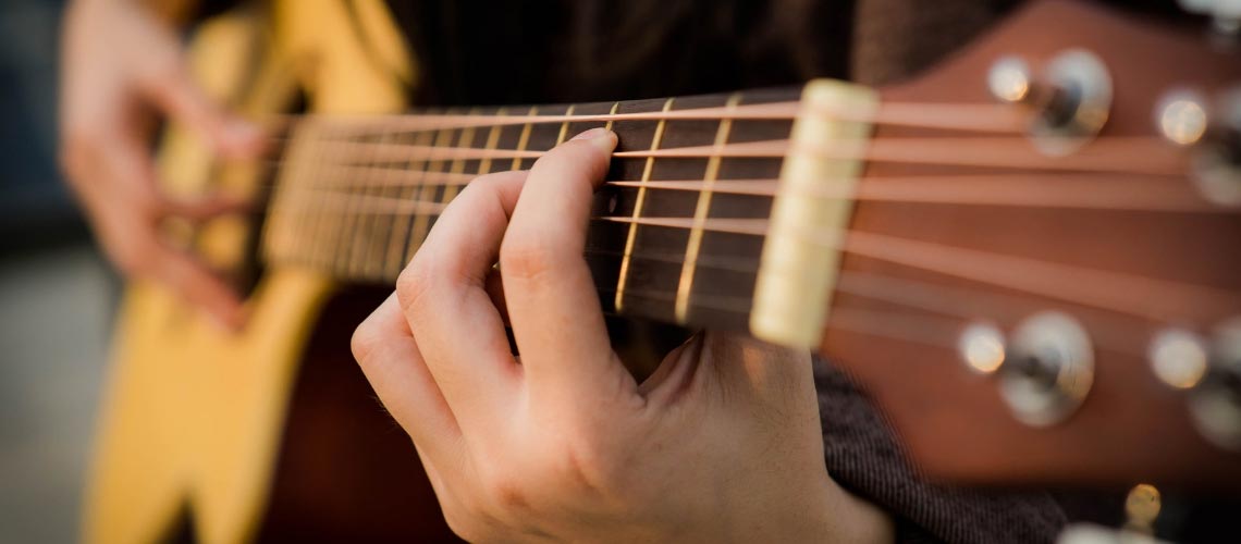 A hand playing on acoustic guitar